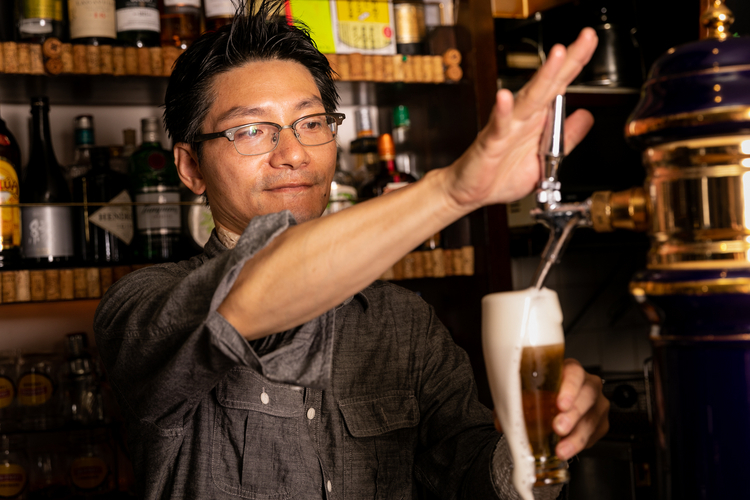 慎重かつ迅速にビールを注ぐ、オーナー兼店長の村上嘉一さん