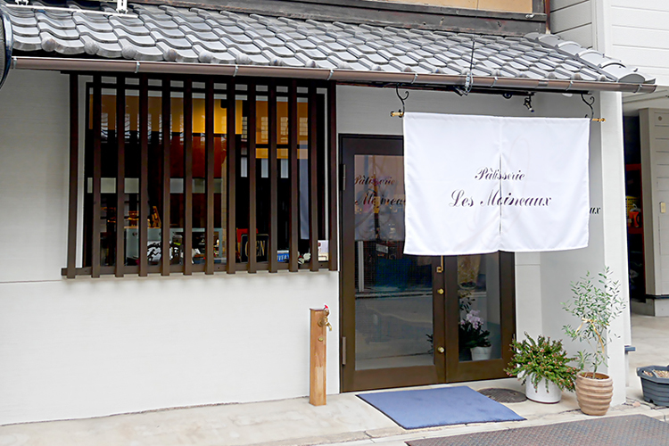 格子窓が京都らしい風情を醸し出す京町家。ロゴ入りの暖簾が目印