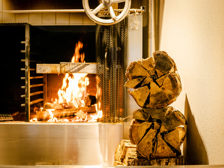 店内奥に設えられた薪焼きの炉窯。テーブル席からも、肉が焼かれていく様子などを見ることができる。薪には楢木を使用している。