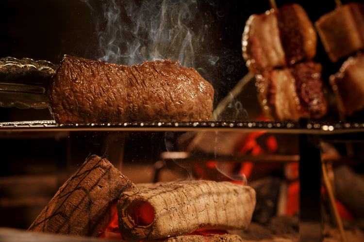 『肉よろず™』の名物メニュー、『原始よろず焼き』。囲炉裏でじっくりと焼かれる逸品です