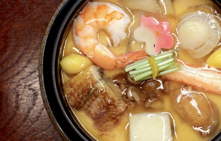 鰹と昆布の合わせ出汁の地に海老、帆立、鰻、烏賊、蟹、焼き雲丹、煮鮑、銀杏、生麩、ナメコの具材が入った茶碗蒸し