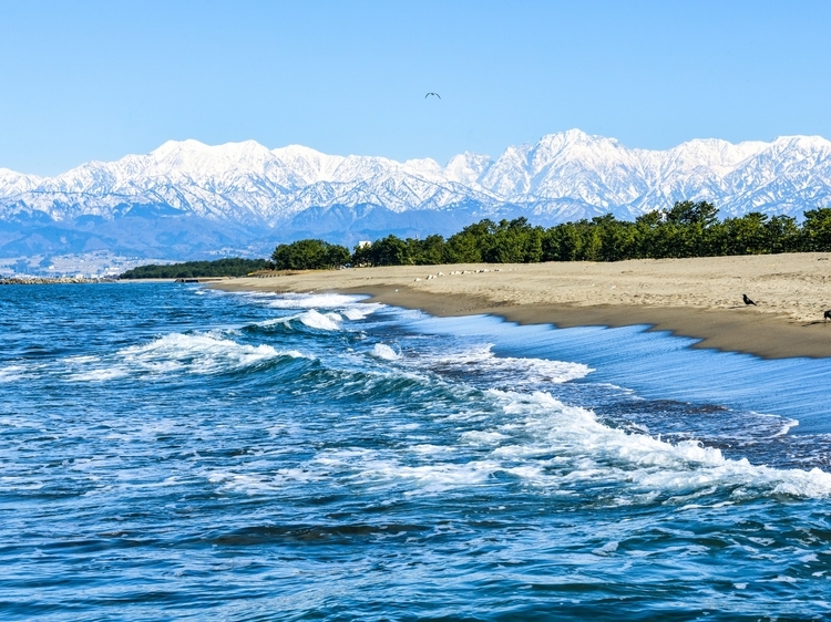富山湾越しに立山連峰を望む、富山独自の海と雪山の風景
