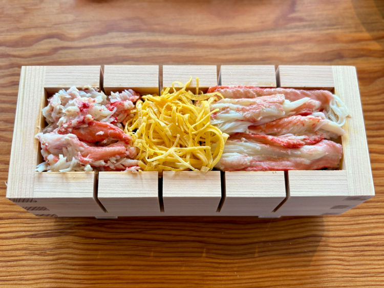 木枠に酢飯、大葉、海苔、カニの身を重ね、最後にそっと押して仕上げます