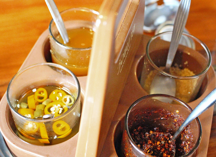 タイのレストランには必ずある調味料セット。左下から時計回りに唐辛子の酢漬け、ナンプラー、砂糖、唐辛子。これで自分好みの味にしていく